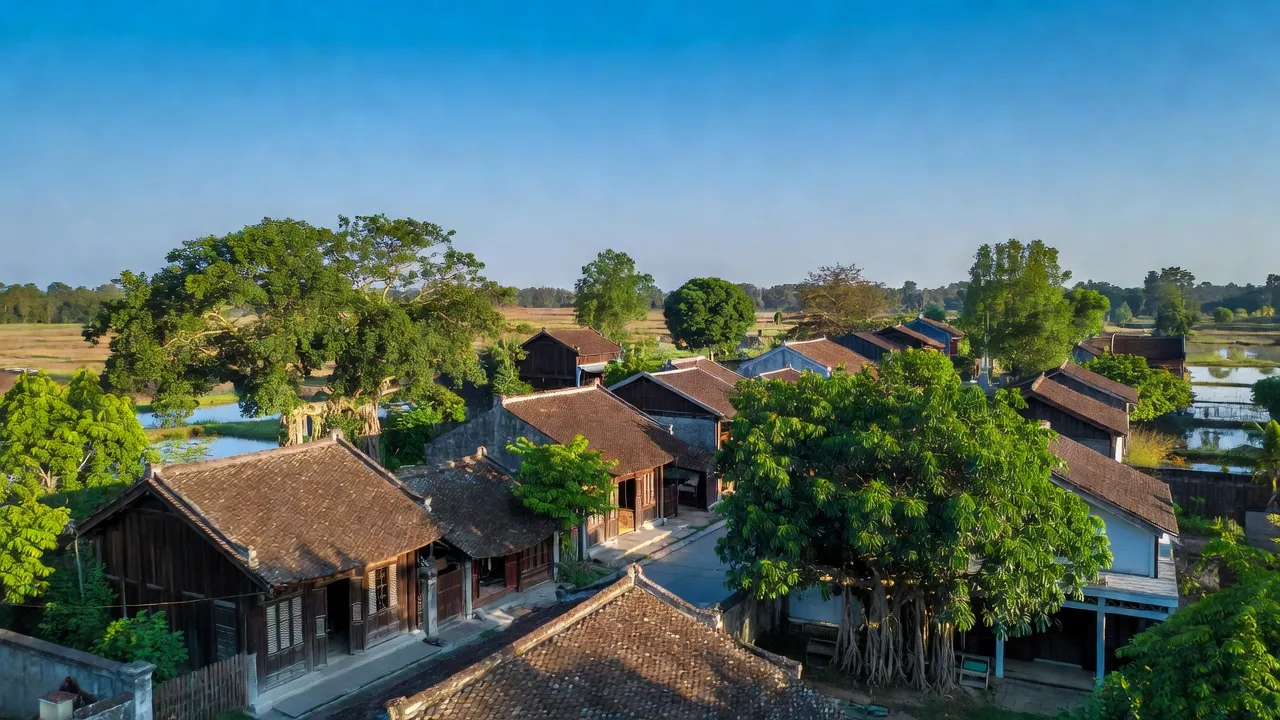 Khung cảnh thị trấn Quỹ Nhất, Nghĩa Hưng, Nam Định, với nhà cổ, cây xanh và bầu trời trong.